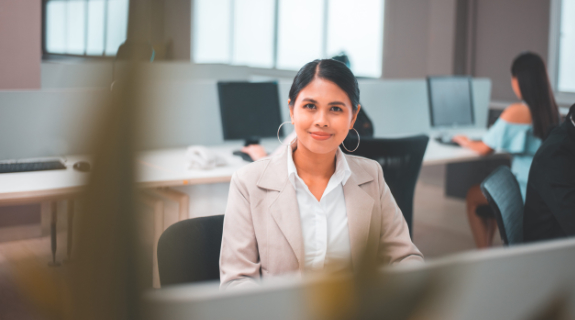 professional young woman in a cubicle office smiling at the camera